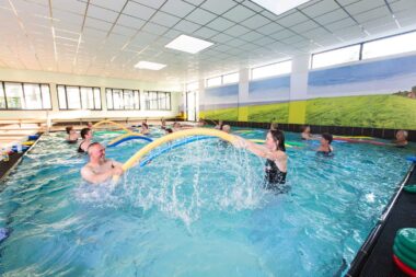 Die Kursteilnehmer machen jeweils zu zweit Übungen mit Poolnudeln.