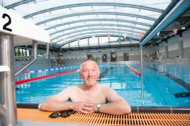 Ein älterer Herr lehnt am Beckenrand. Im Hintergrund sieht man das Sportbecken der GraftTherme.