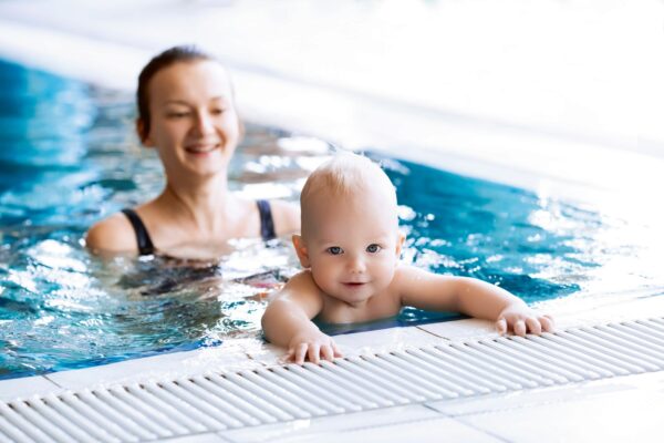Eine Mutter ist mit ihrem Baby im Schwimmbecken beim Babyschwimmen.