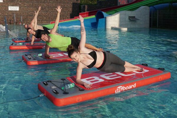 Mehrere Kursteilnehmer machen Übungen auf ihren BeBoards im Wasser.